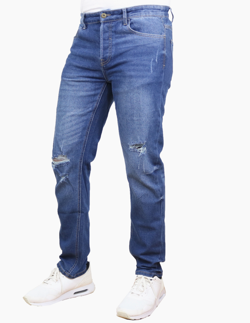 A pair of men's medium wash blue denim jeans with distressed rips on the thighs and knees, styled with white sneakers against a plain white background.